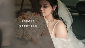 Young bride wearing a white veil and gown looking downward with a somber expression.