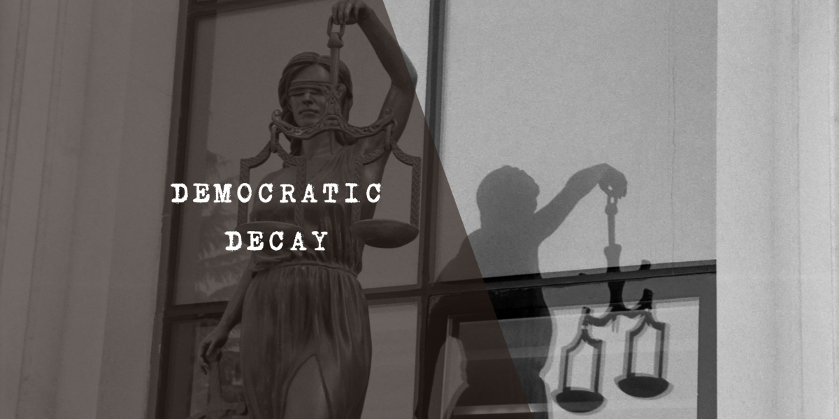 A black and white, high-contrast image depicting the statue of Lady Justice holding her scales, with her shadow cast on the wall behind her resembling the silhouette of a corrupt or grubby man to symbolise judicial capture.