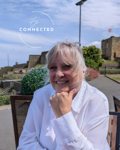 Caroline Saul smiling with a castle in the background, featuring the Stay Connected logo watermark.